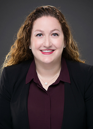 Professional woman with curly hair smiling confidently.